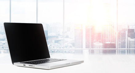 Laptop on table in office with panoramic view of modern downtown skyscrapers at business district