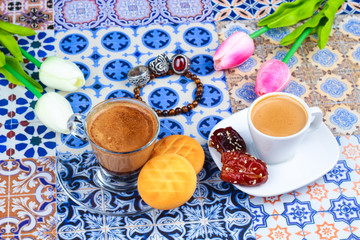 Cup of Arabian Coffee on an Oriental Colorful Background / Cup of Espresso on an Oriental Colorful Background with Flowers, Rings, and Tamr dates 