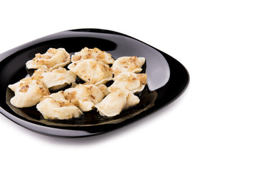 Fresh dumplings on a black plate seasoned with crispy onions.