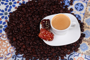 Cup of Arabian Coffee on an Oriental Colorful Background / Cup of Espresso on an Oriental Colorful Background with Flowers, Rings, and Tamr dates 