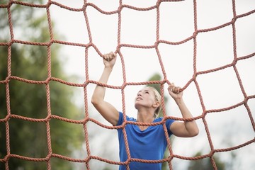 Woman climbing a net during obstacle course