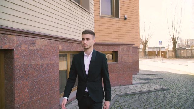 Young businessman walking towards to camera on the street 4K