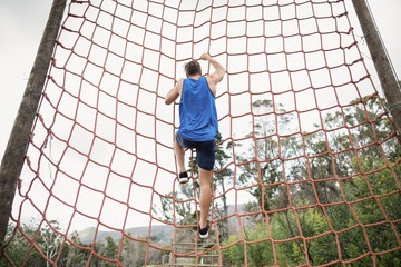 Man climbing a net during obstacle course