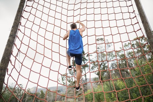 Man climbing a net during obstacle course - Powered by Adobe
