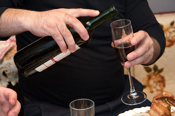 man pouring red wine into a wineglass.