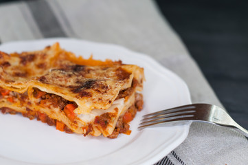 Close-up of a traditional lasagna made with beef bolognese sauce served on a white plate