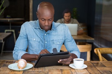 Man using tablet computer at table in coffee shop