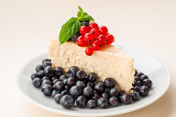 Cheesecake New - York decorated with blueberries, red currants and mint