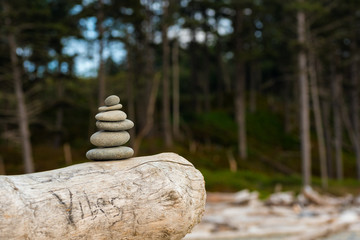 Small stack of flat stones resting on a log on a Pacific Coast beach