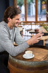 Man using smart phone at table in coffee shop