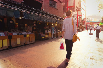 Naklejka premium Młoda kobieta spaceru na ulicy w Asakusa Tokio o zachodzie słońca patrząc w przyszłość