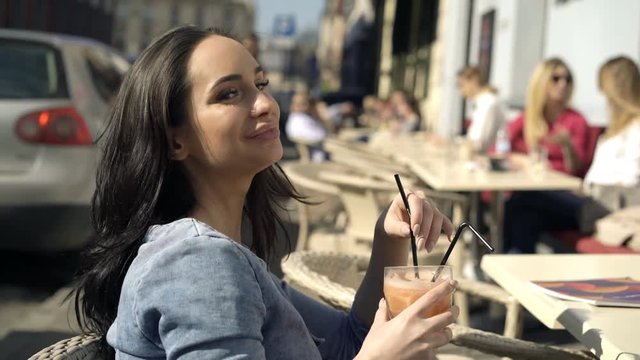 Pretty, happy woman drinking cocktail sitting in cafe 
