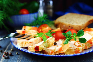 желе из мяса курицы и овощей на блюде со свежей зеленью,помидорами и перцем