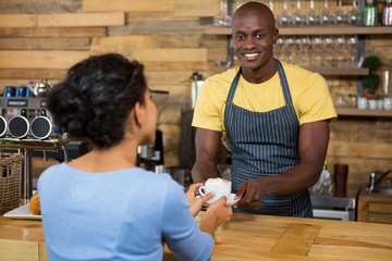 Portrait of barista serving coffee to customer in cafe