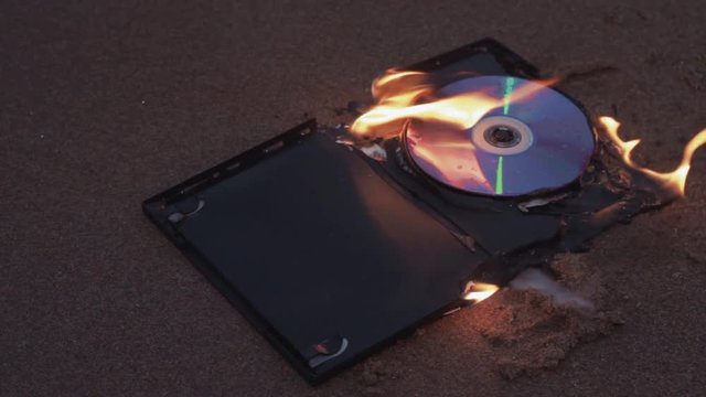 data cd dvd laser compact disc case on fire on the wet sand at coast HD