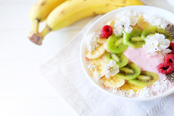 Raspberry and banana smoothie bowl with kiwi slices, shredded coconut and chia seeds.