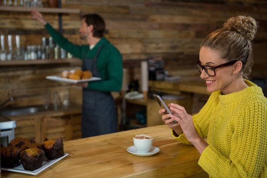 Happy woman using mobile phone in coffee shop - Powered by Adobe