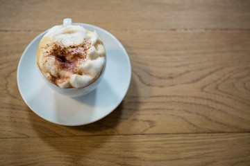 Coffee cup with creamy froth on table in cafeteria