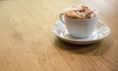 Coffee cup with creamy froth on table at cafe