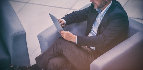 Businessman sitting on chair using digital tablet