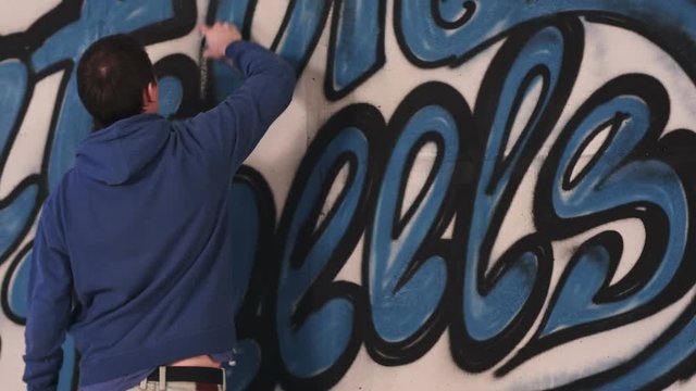 Young urban painter drawing graffiti on the wall