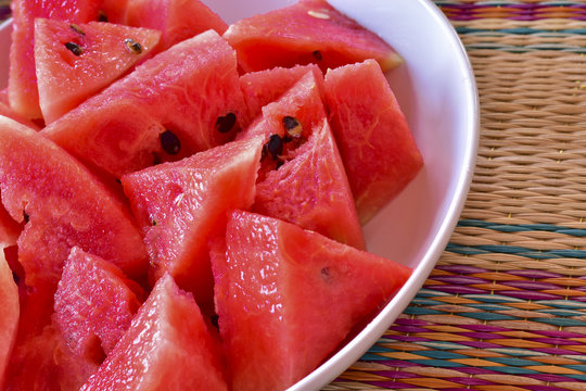Close up of chopped red watermelon in white plate put on local mat, fresh fruit