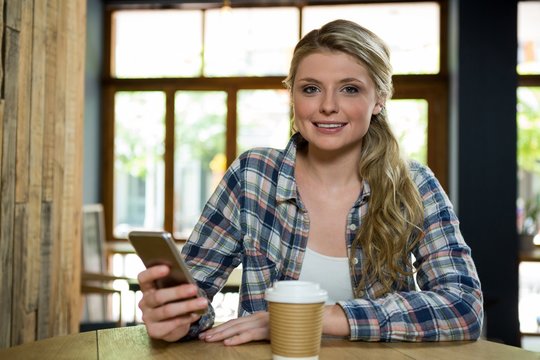 Portrait of young woman using mobile phone in cafe