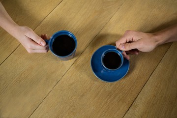 Couple hands holding coffee cups in cafe