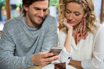 Couple using smart phone at table in coffee shop