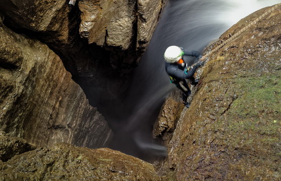 Explore the breathtaking Mayei Cave in Ecuadorian Amazonia with a speleologist inside a deep waterfall entrance shaft,capturing the blurred motion of adventure.