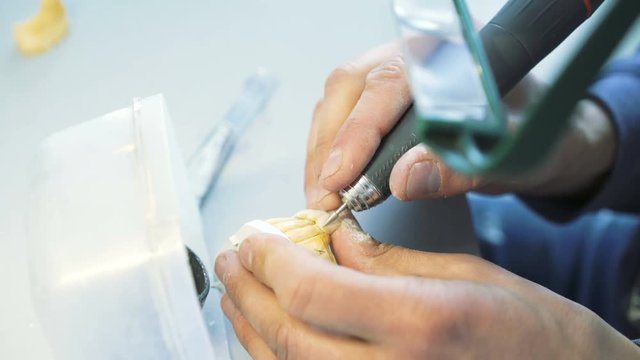 Closeup of grinding teeth crowns with instruments in dental lab in 4K