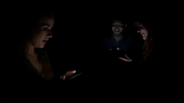 Three young people spending their time in the same room but using social media to socialize