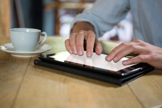 Man using digital tablet at table in coffee shop