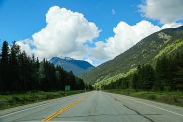 Road between mountains with clouds in the sky