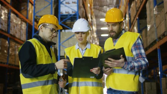 Team of Male and Female Inspectors/ Workers/Auditors Have Discussion in Big Warehouse with Rows of Racks with Pallets. Shot on RED EPIC-W 8K Helium Cinema Camera.