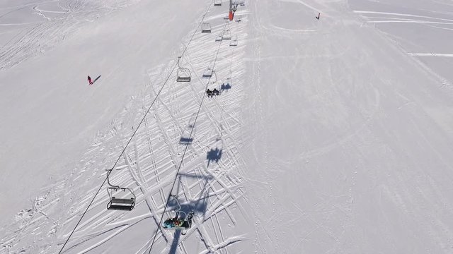 Top view frome drone of poma lift in ski mountain resort with people in slowmotion