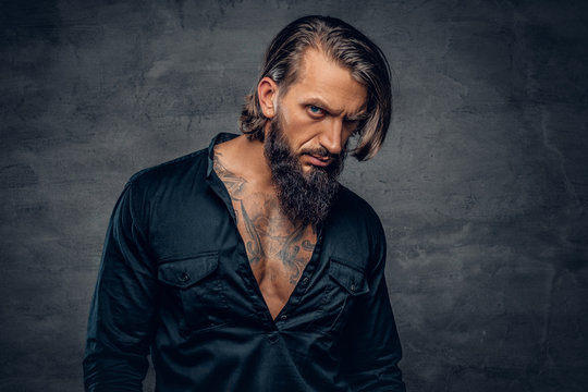 A man with long hair and tattoos on his chest dressed in a black shirt.