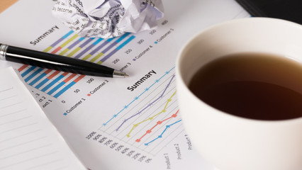 Close up of Business workplace with analyzing chart and coffee cup.