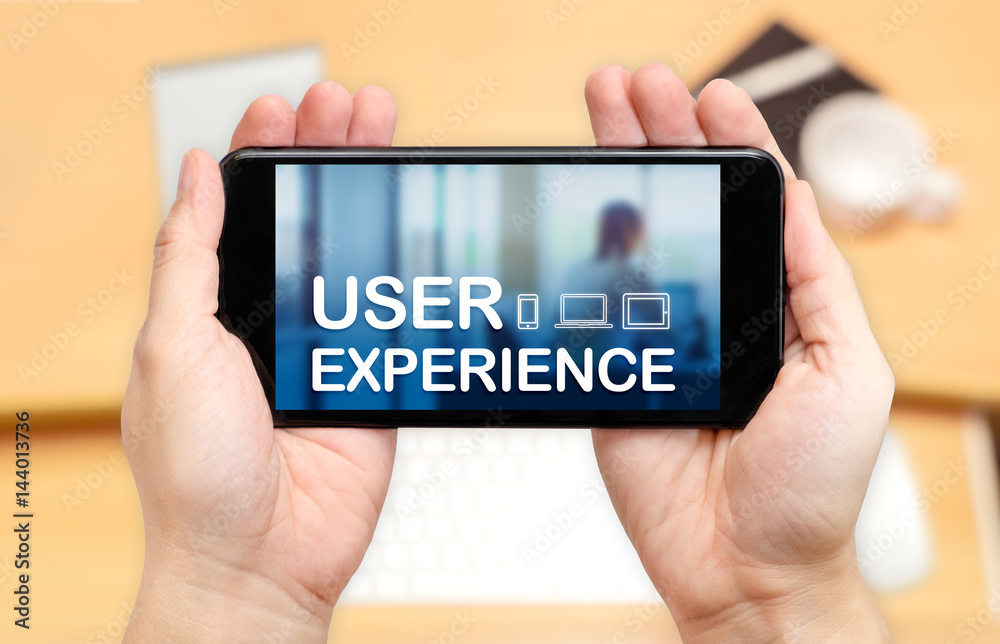 Aufkleber watching two hand holding mobile phone with user experience word on screen and blur desk office back