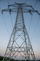 big electric power tower at sunset with a yellow moon in the background