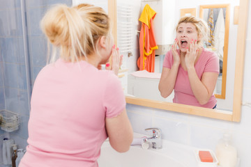 Scared woman washing her face under sink