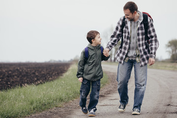 Fototapeta premium Father and son walking on the road at the day time.