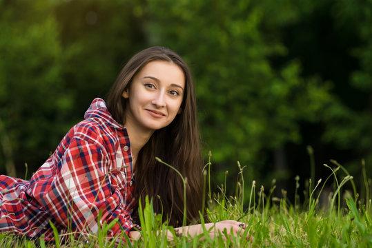 woman in jeans and shirt resting. Lays on the fresh grass