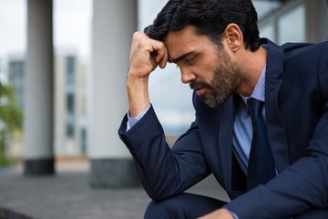 Depressed businessman sitting with hand on forehead