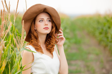 photo of beautiful young woman standing near the growing wheat