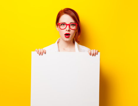 photo of beautiful young woman holding empty poster on the wonderful yellow studio background