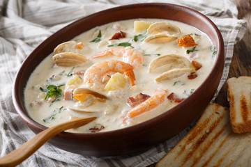 Delicious clam chowder soup with shellfish and bacon close-up on a in a bowl. horizontal