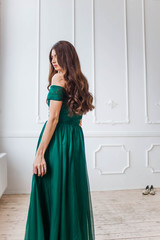 beautiful sad girl in a green dress looking down on white background