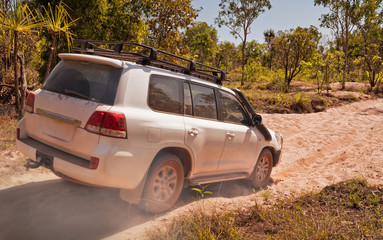 Fototapeta na wymiar Offroad vehicle driving through dry riverbed. Northern Territories, Australia