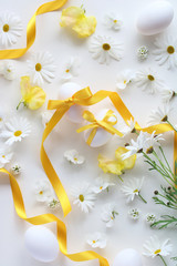 Easter eggs with yellow bow on beautiful spring flowers background